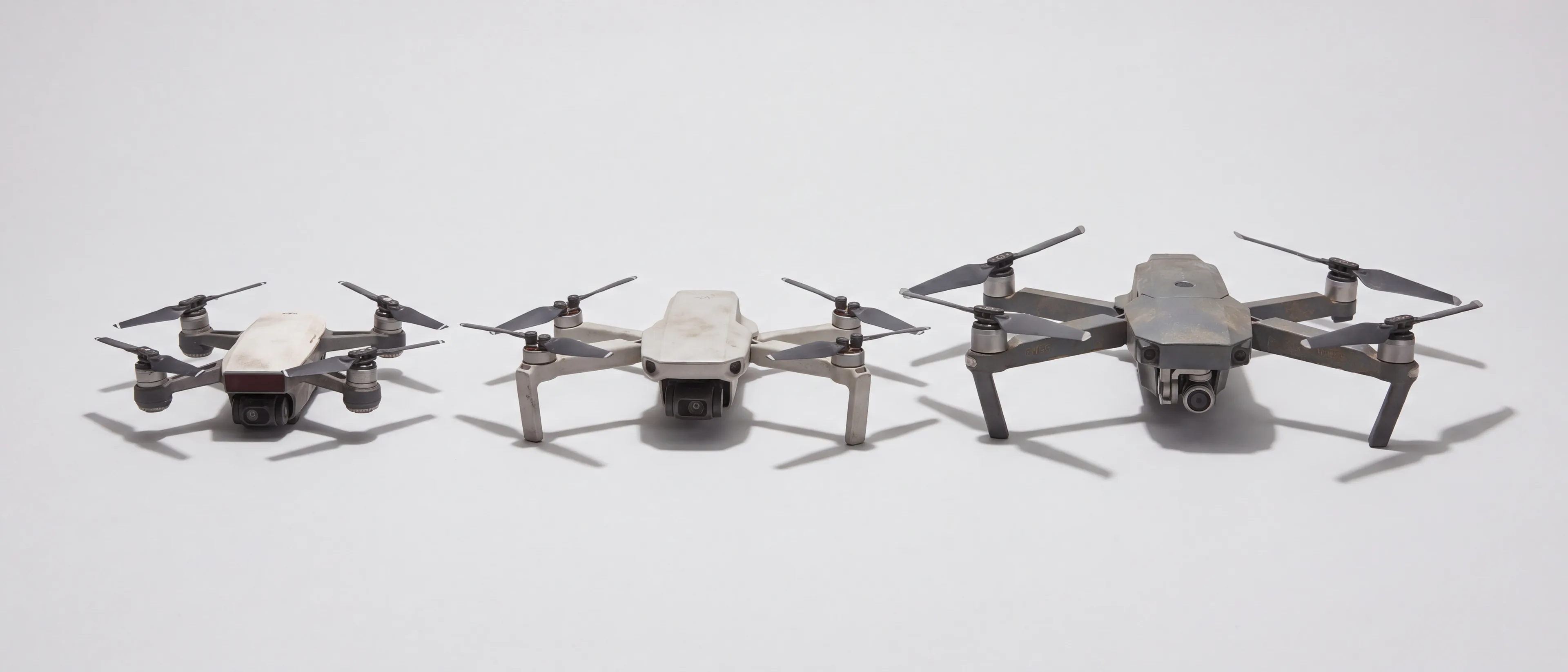 Drie compacte drones naast elkaar op een lichtgrijze ondergrond, van klein naar groot