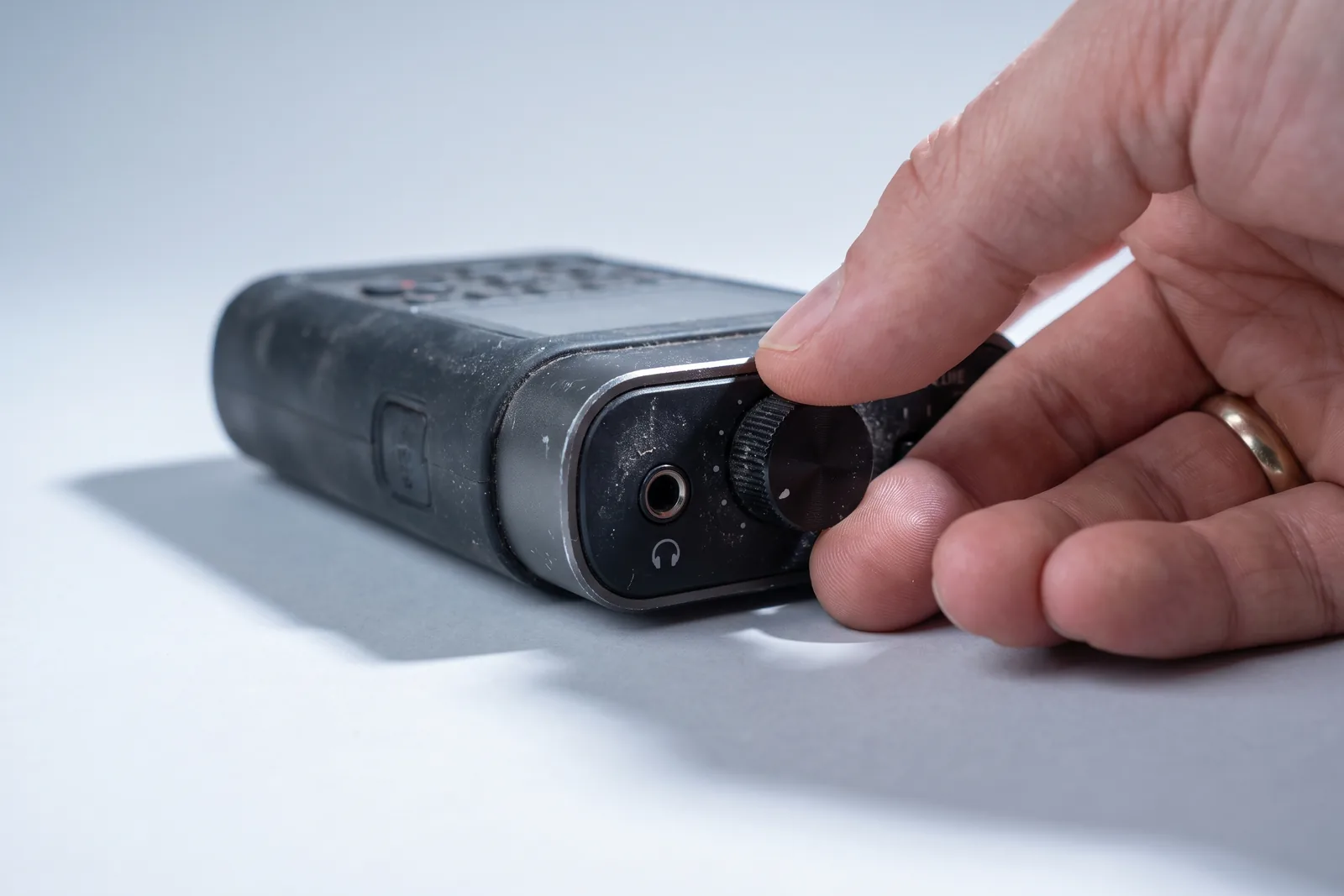 Hand aan de gain-knop van een audiorecorder