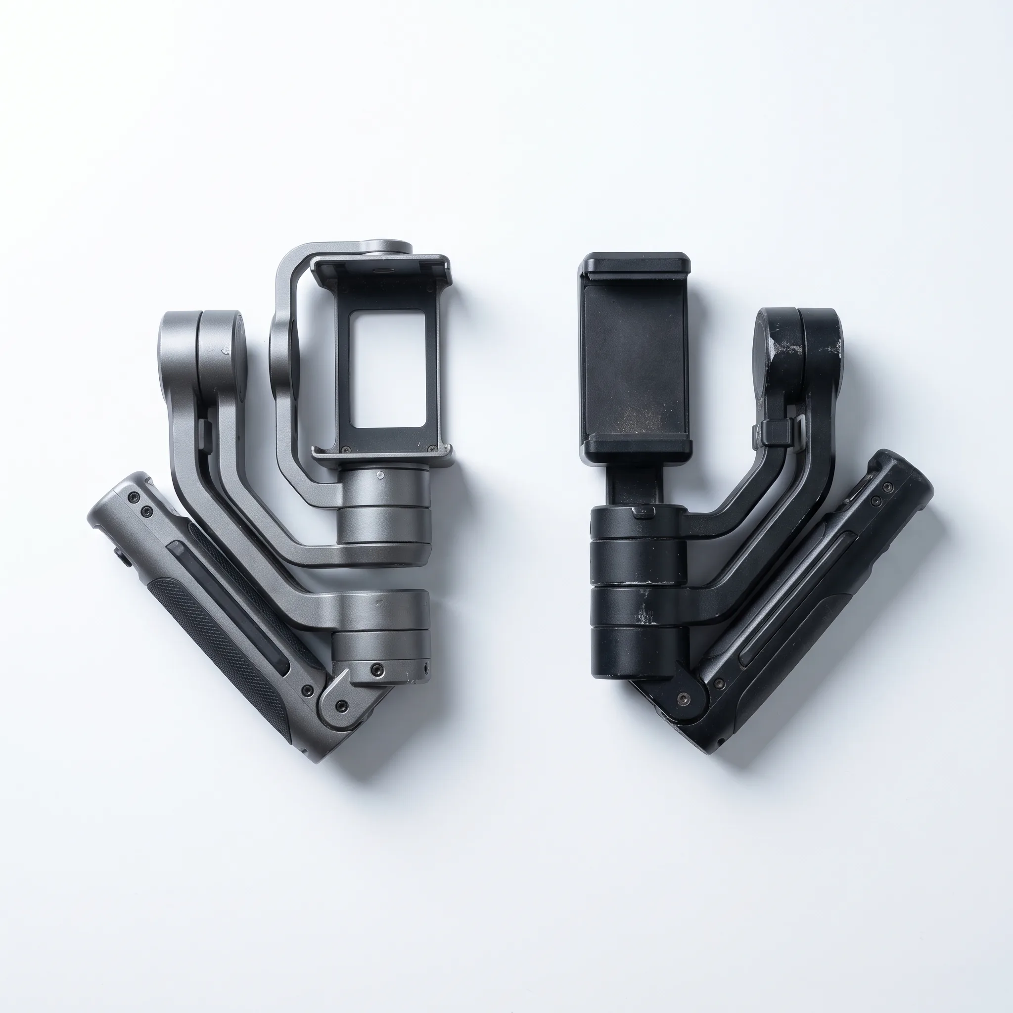 Twee gimbals naast elkaar op een witte ondergrond, één met een camerabeugel en één met een telefoonklem