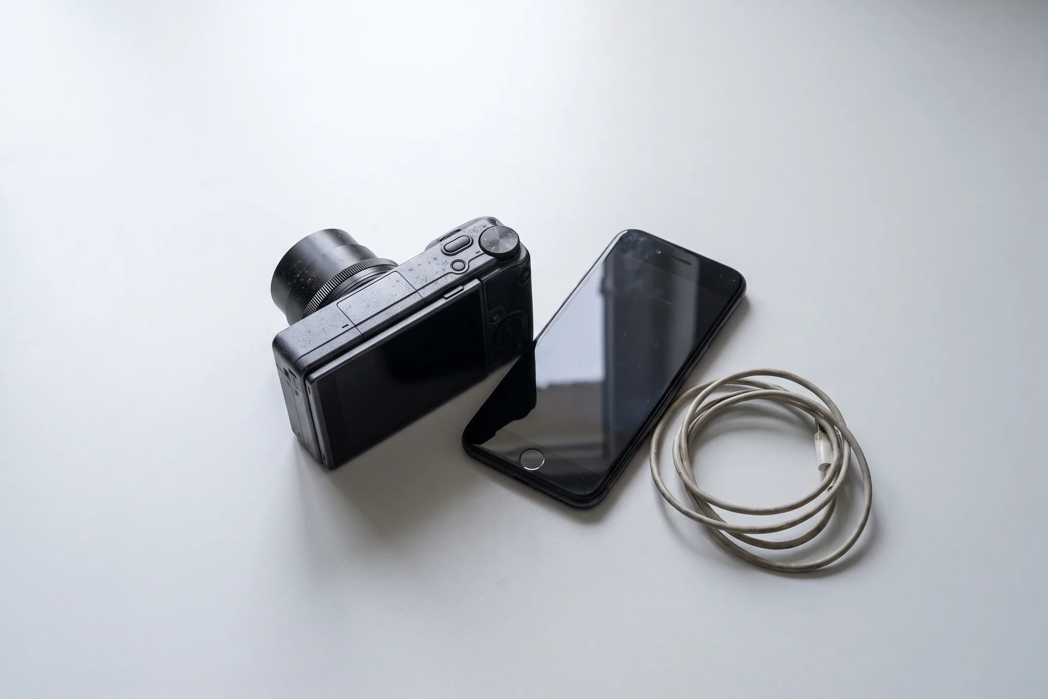 Een camera en een telefoon naast elkaar op een bureau, allebei uit